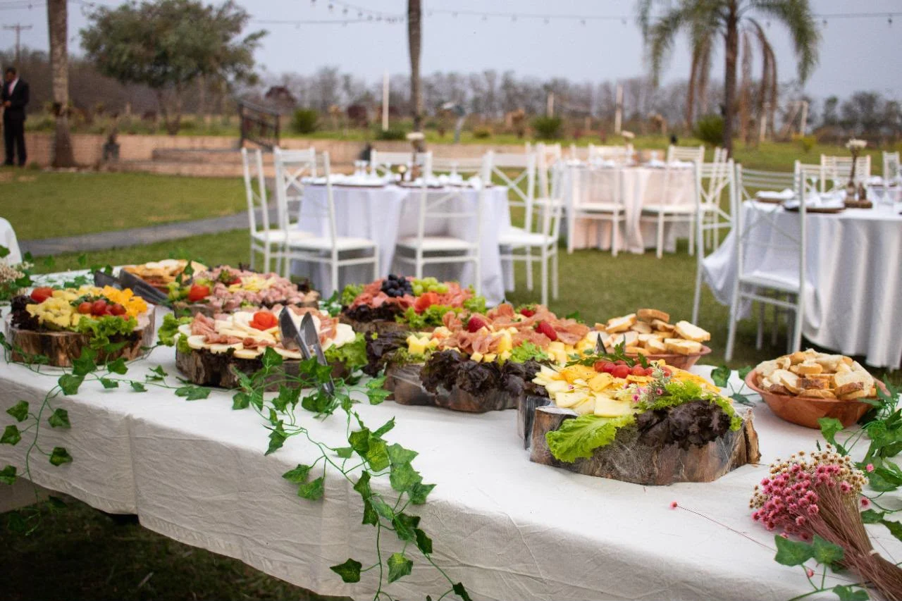Mesa gastronômica ao ar livre com frutas, queijos e flores